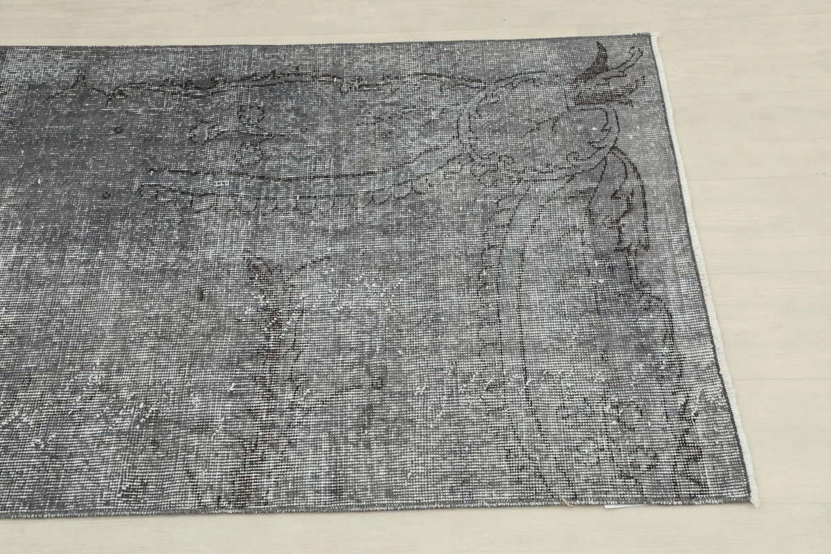 Close-up of one end of the rug, showing faded geometric motifs and subtle color variations