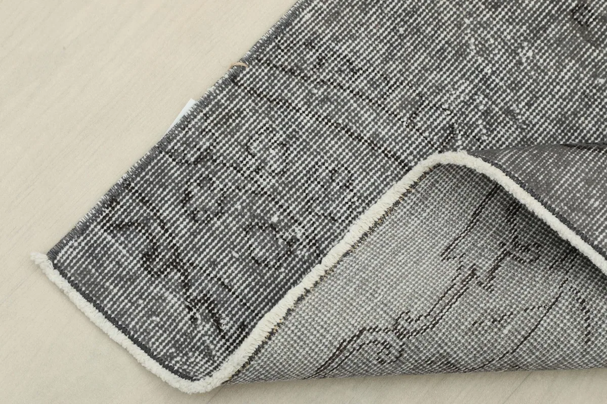 Corner of the rug folded back, showing the cotton foundation and reverse side of the knotting