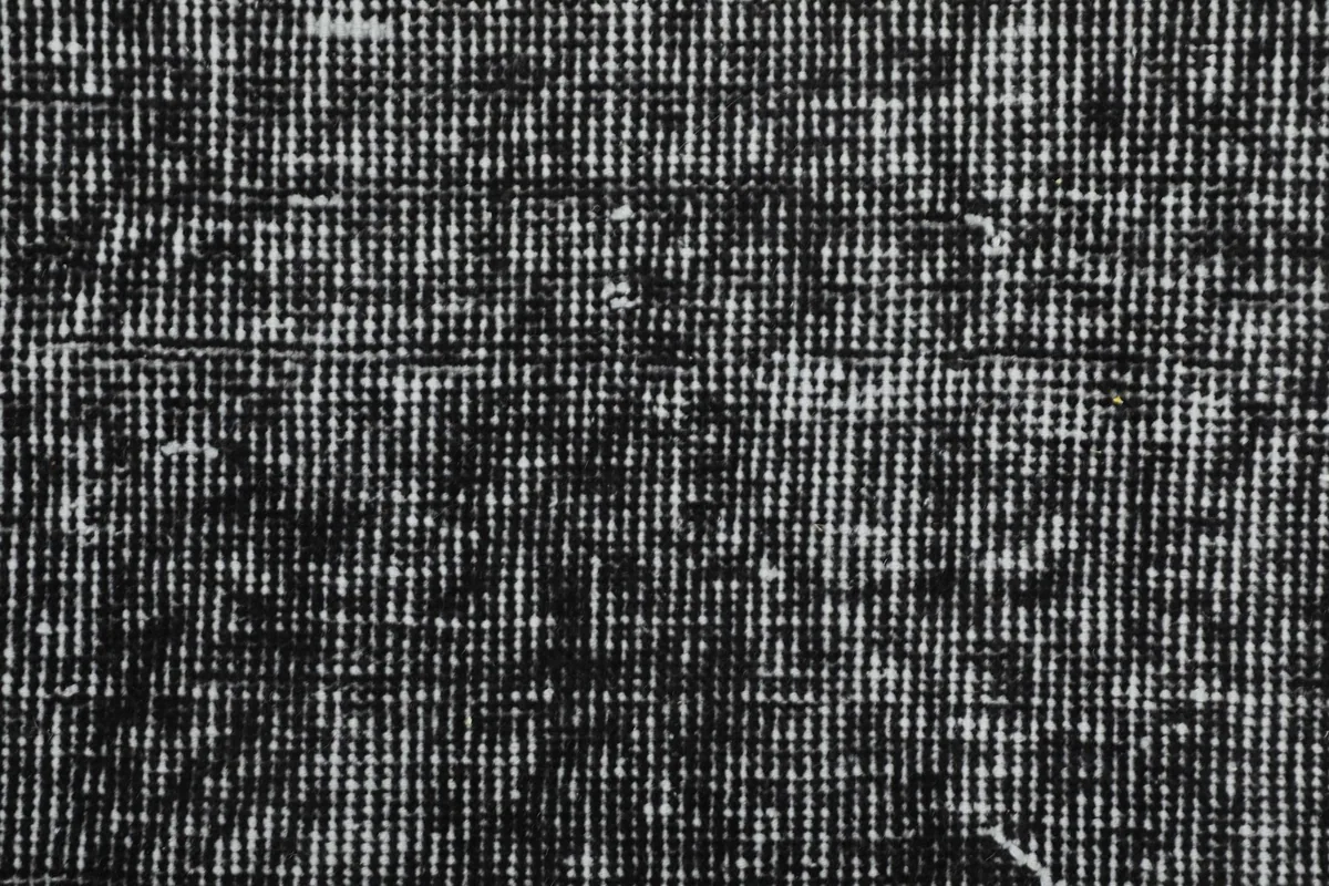 Extreme close-up of the rug's wool pile, showing the tight knots and varied texture from its vintage condition.