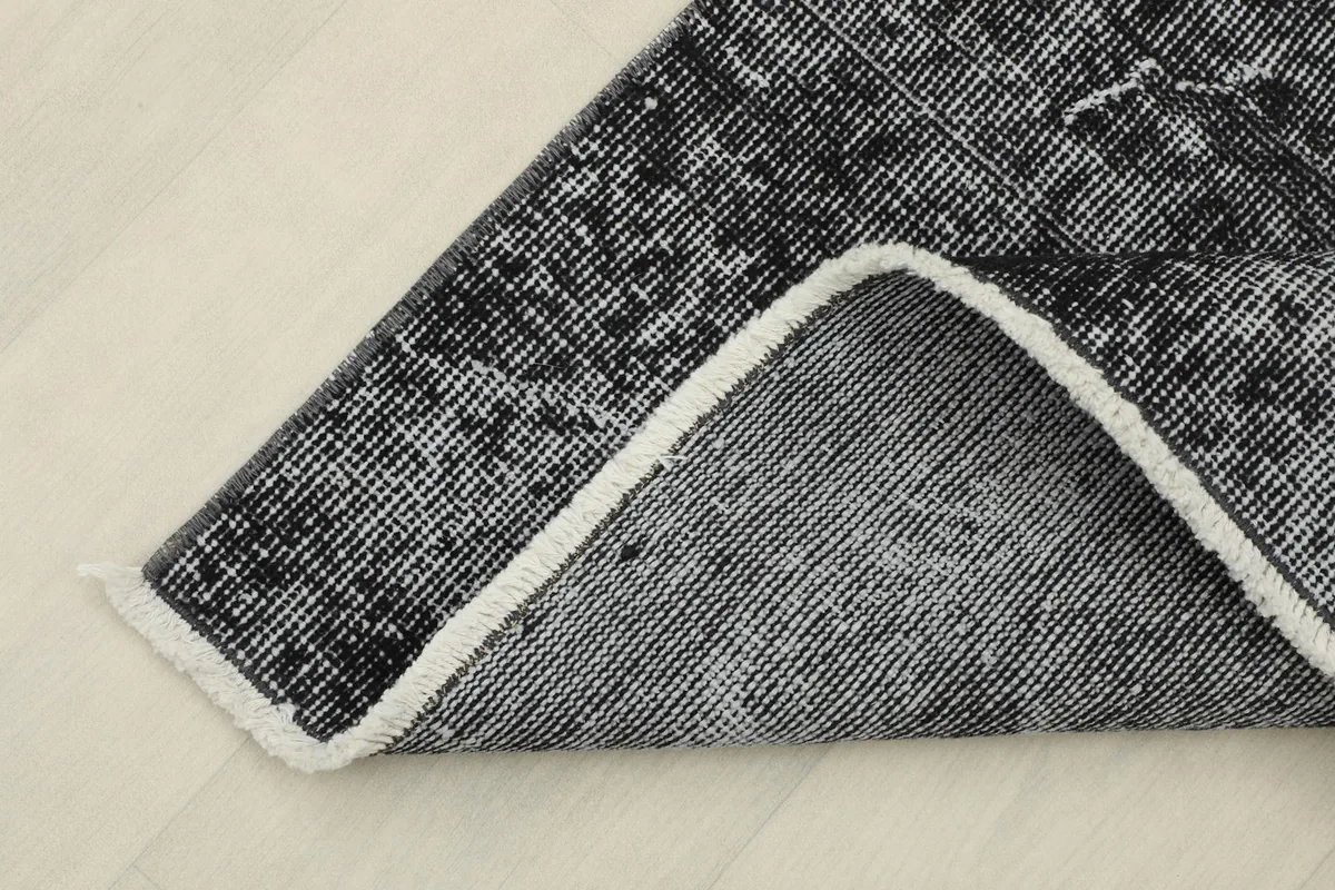 View of the rug's underside, showing the cotton foundation and the reverse of the hand-knotted wool pile.