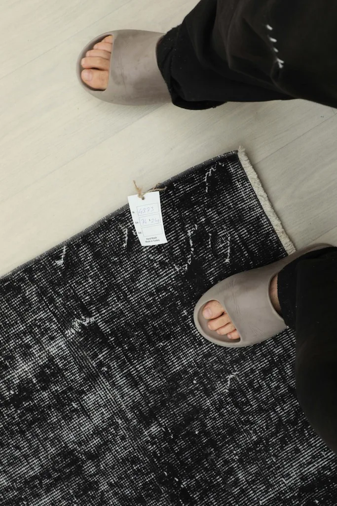 Overhead view with feet, demonstrating the rug's scale and texture in a real-life setting.