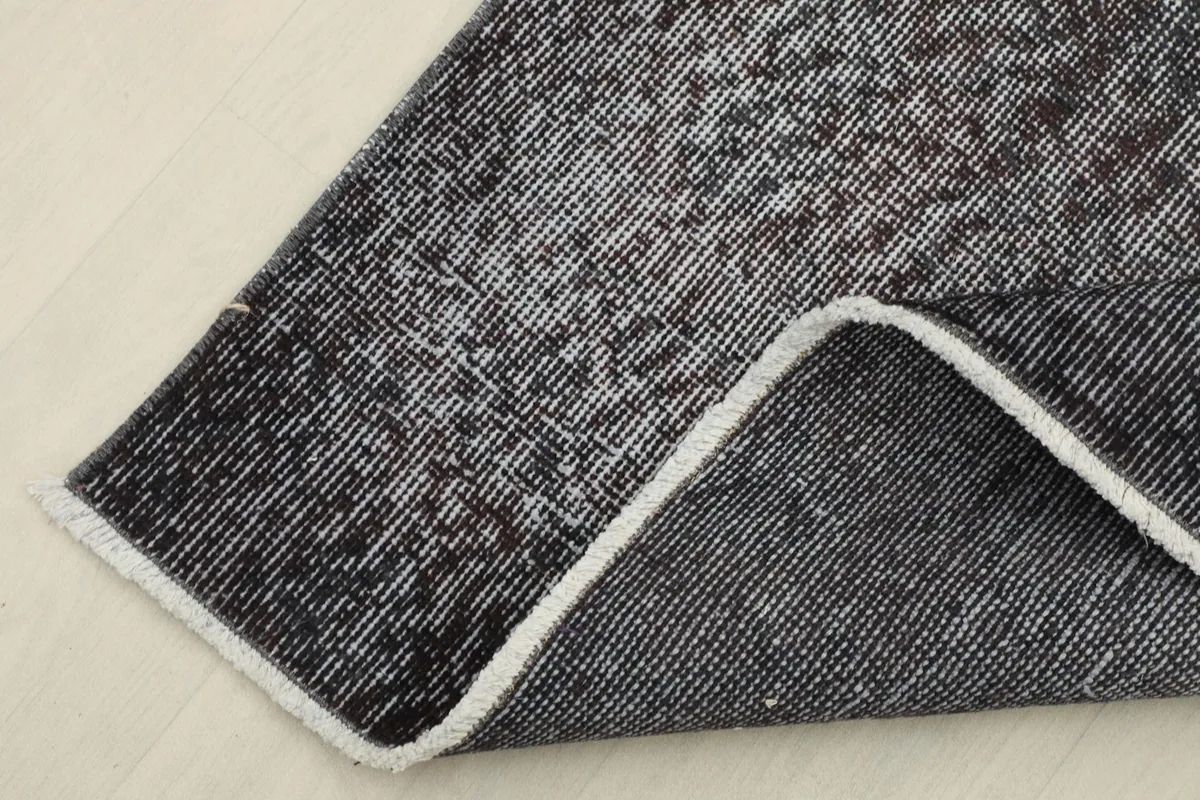 View of the back of the rug, showing the cotton foundation and the reverse of the hand-knotted pile.
