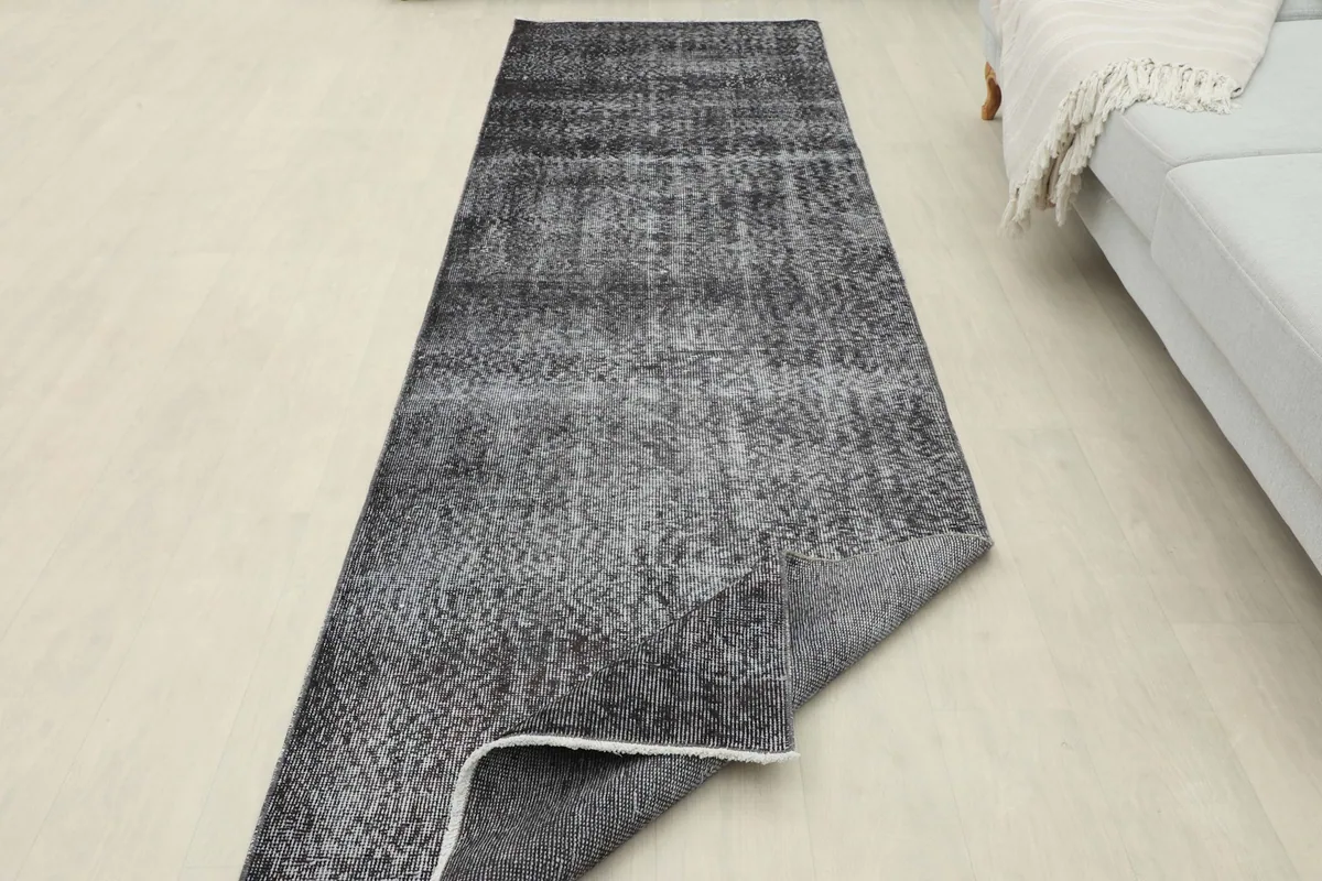The runner with a corner folded back, illustrating the thickness and flexibility of the vintage wool rug.