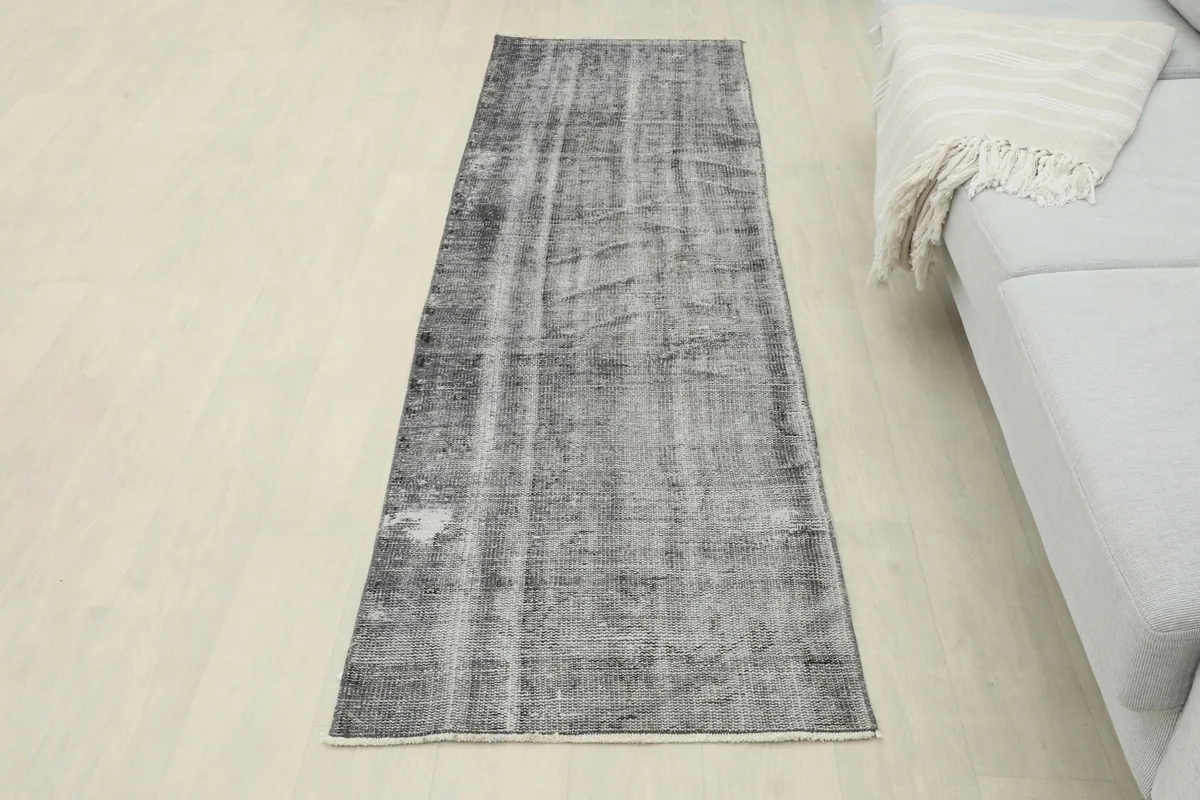 Full view of the charcoal gray runner rug in a room setting, positioned in front of a sofa.