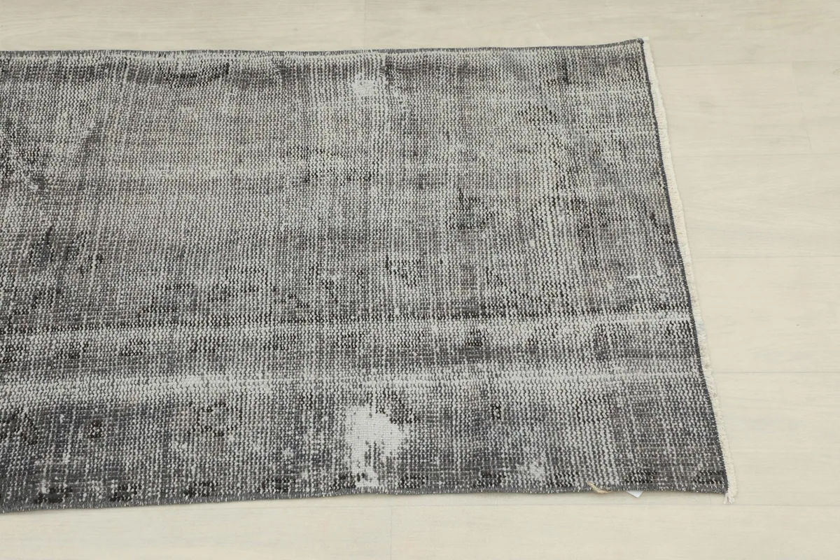 Close-up of one end of the vintage runner rug, highlighting the faded charcoal and gray tones.