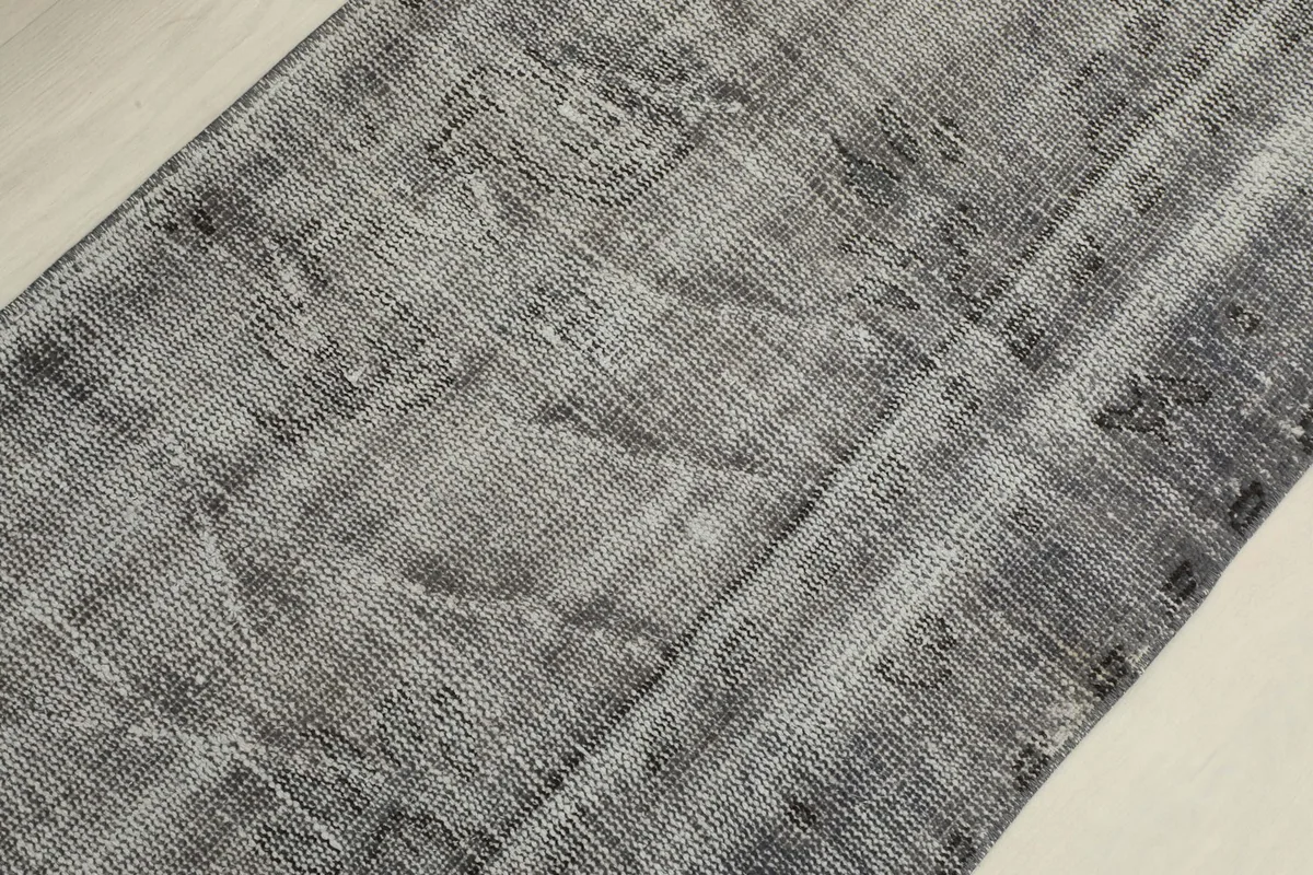 Angled close-up of the rug's surface, revealing the distressed texture and low pile of the wool.