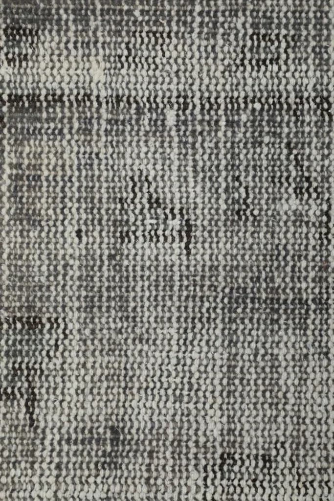 Extreme close-up of the hand-knotted wool pile, showing the tight weave and varying gray shades.