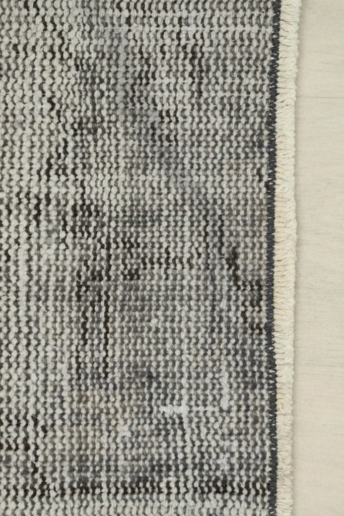 Close-up view of the rug's edge and the short, natural ivory fringe on the cotton foundation.