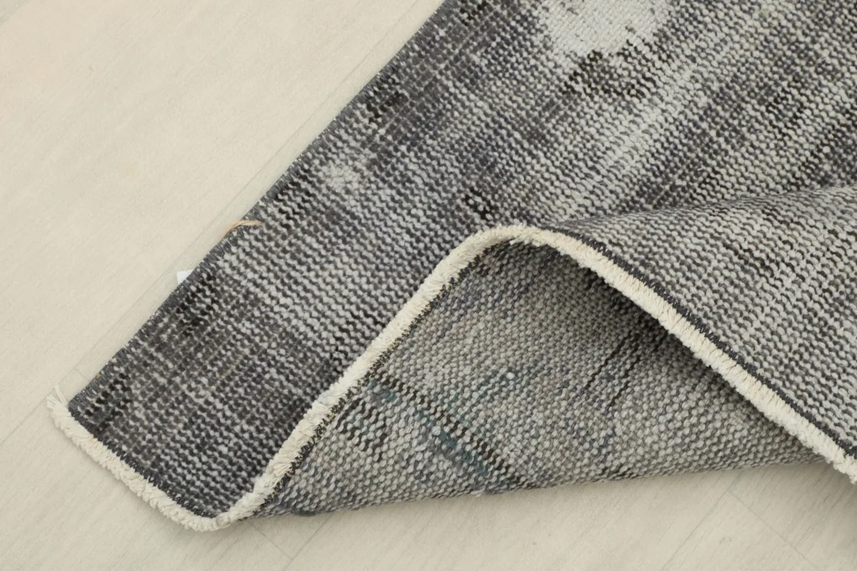 Corner of the runner rug folded back, revealing the reverse side and the hand-knotted cotton foundation.