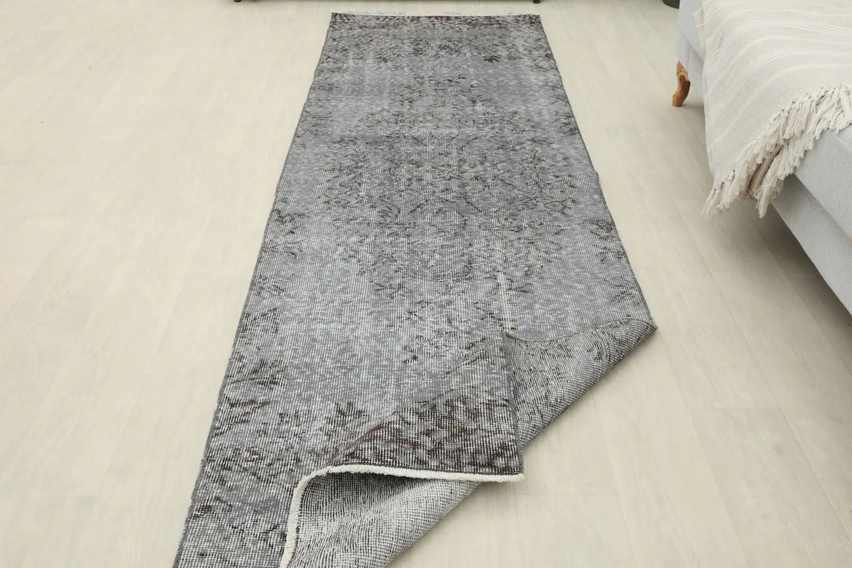 The runner rug with one corner folded back, revealing the reverse side