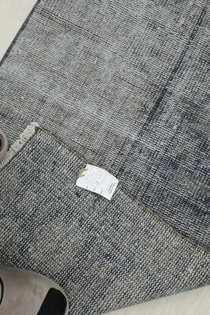 Close-up of the back of the rug, showing the hand-knotted construction and material tag.