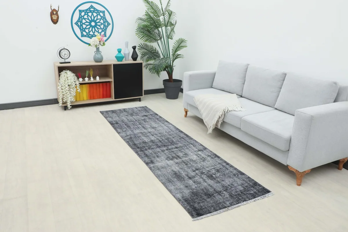 Runner rug in a modern living room setting, extending from a light gray sofa.