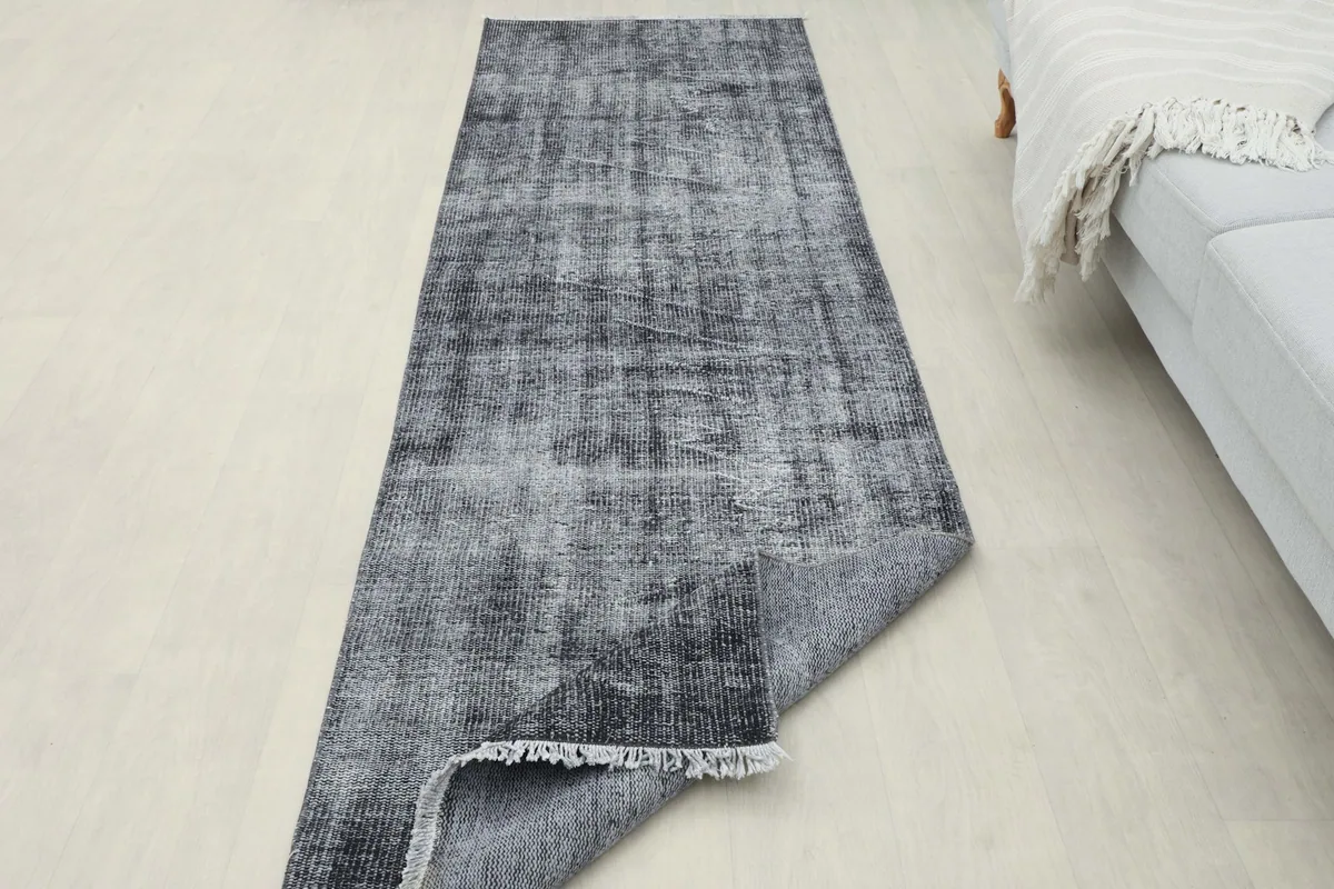 Runner rug partially folded in a room setting, displaying both the pile and the back of the rug.