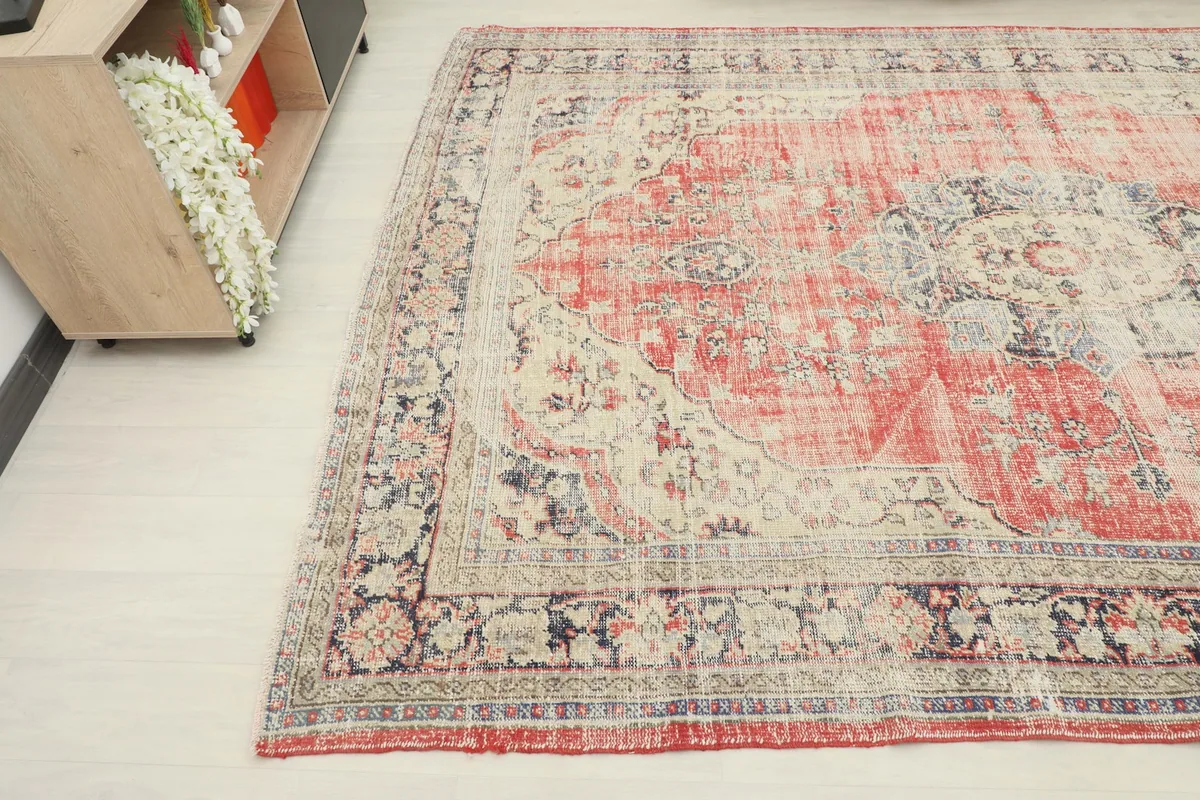 Opposite corner view of the vintage rug, showing the blend of red, cream, and navy tones.