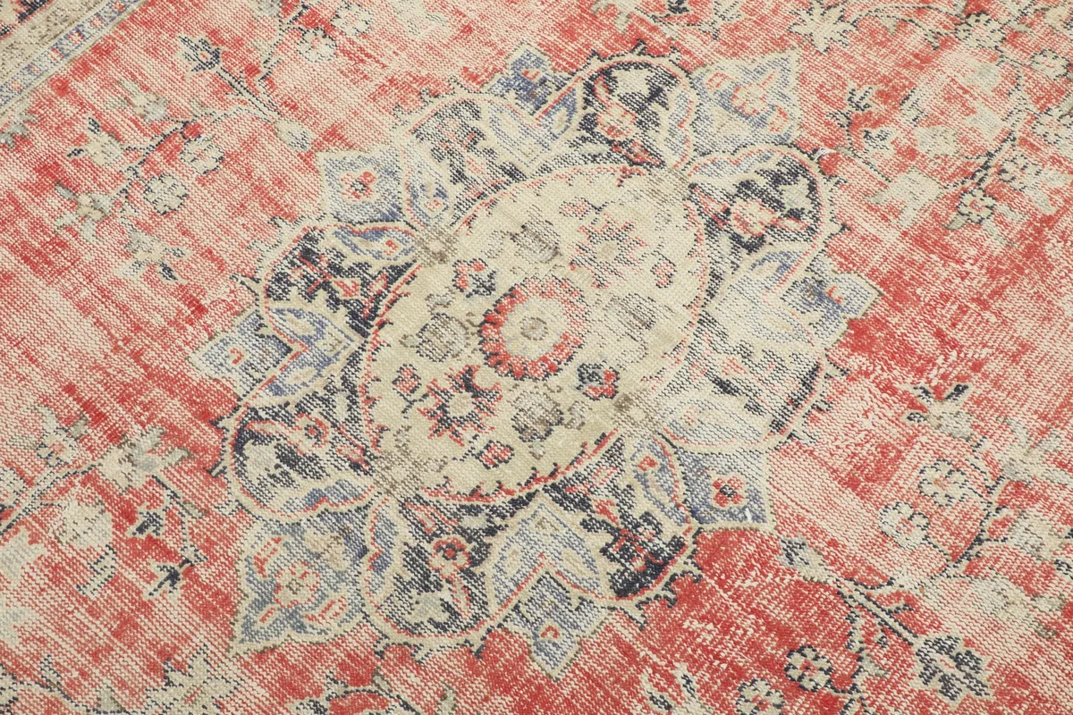 Close-up of the central medallion motif with intricate floral designs in cream, red, and navy.