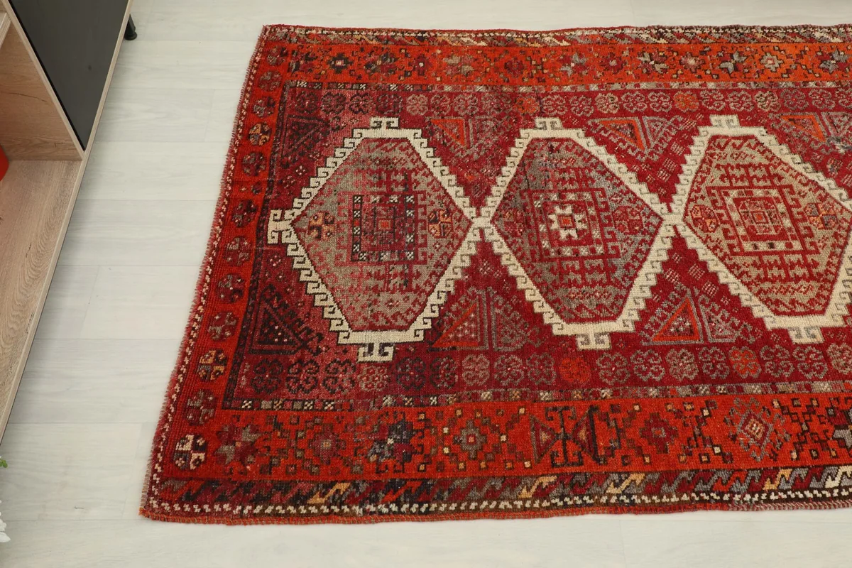 Diagonal view of the vintage rug highlighting the central geometric medallions and field