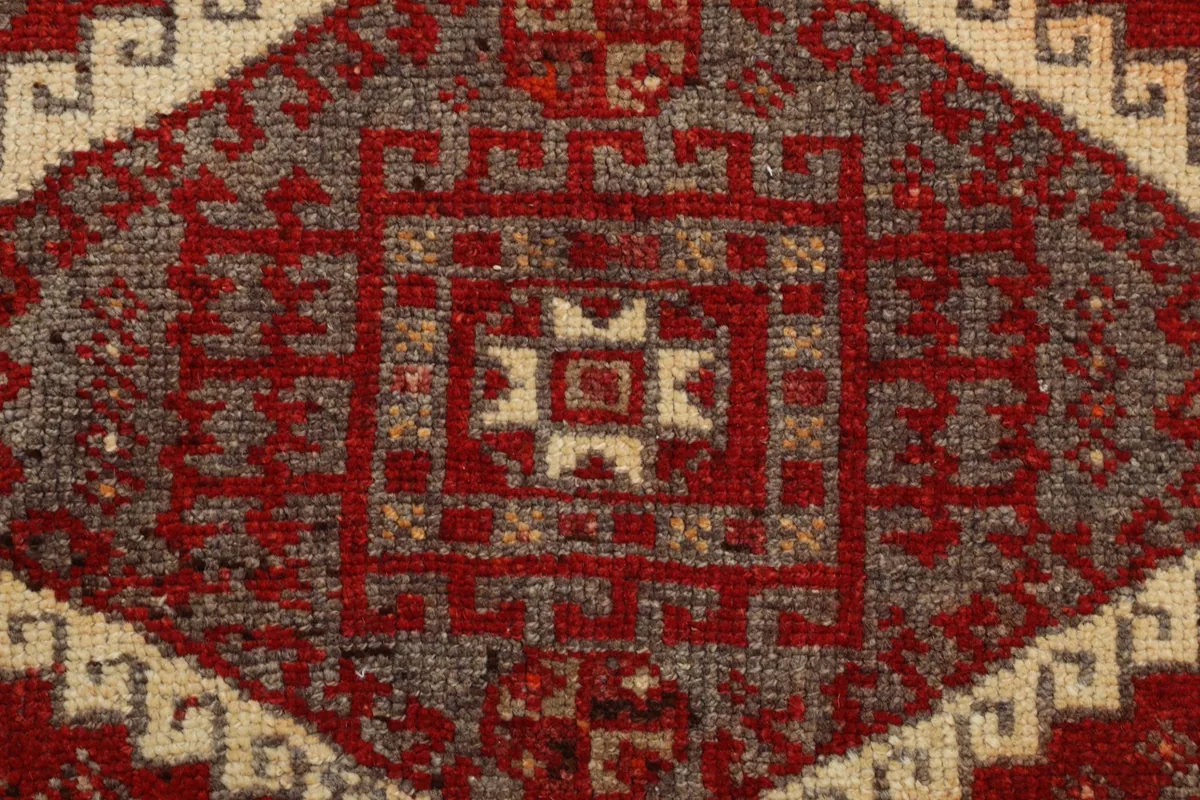 Extreme close-up of a central geometric motif in red, gray, and beige