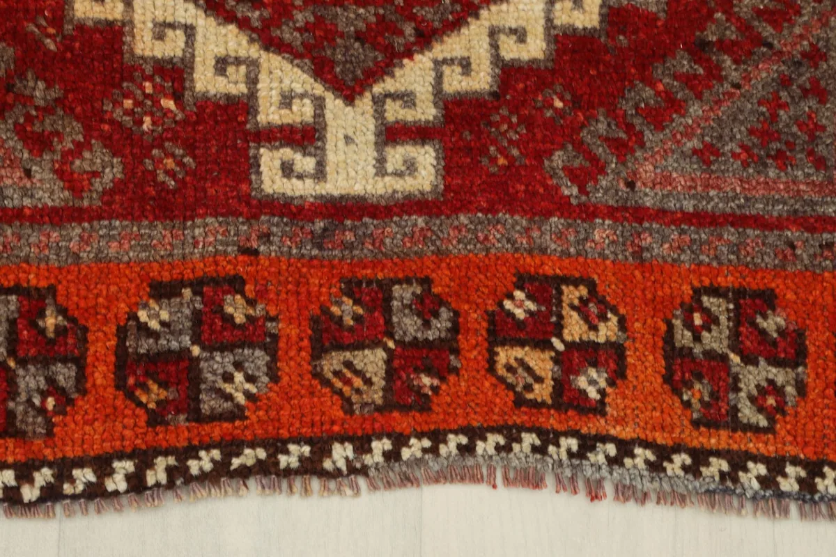 Close-up of the orange border with circular tribal designs and fringe detail