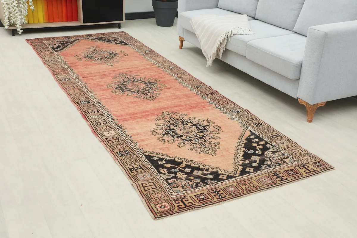 Long view of the rose runner rug placed in a bright room beside a light gray sofa