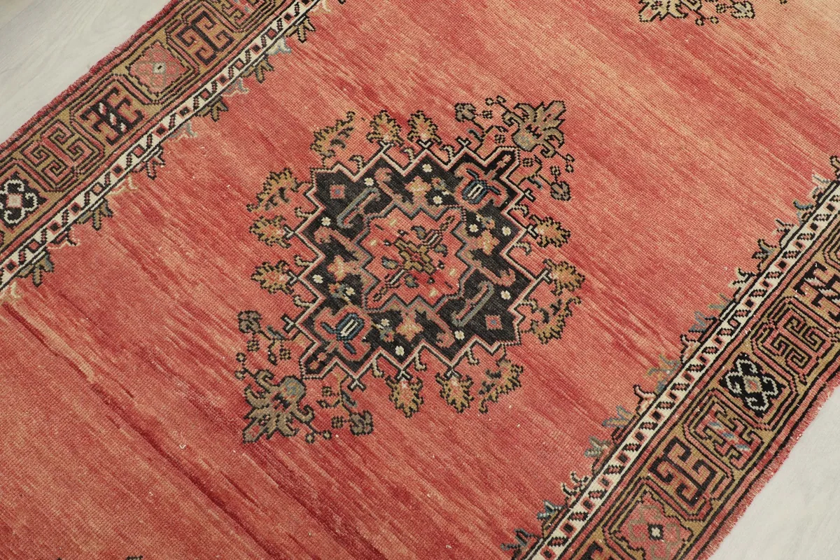 Close-up of a central geometric medallion with black, tan, and subtle blue details on the rose field