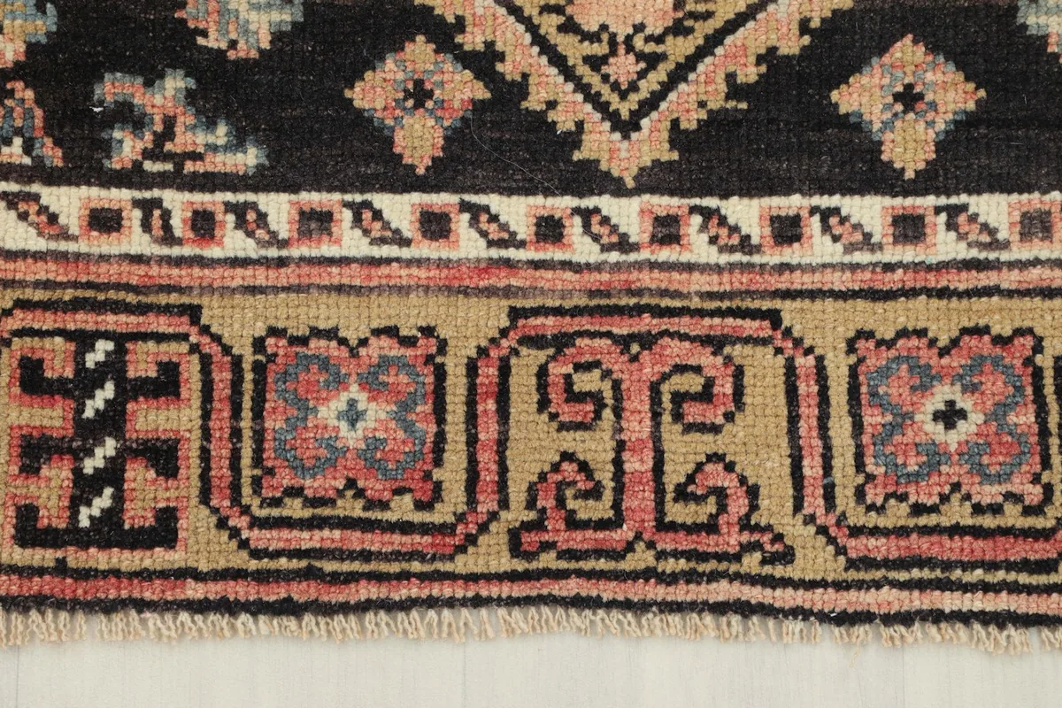 Close-up of the runner's side border, featuring small geometric motifs in tan and rose