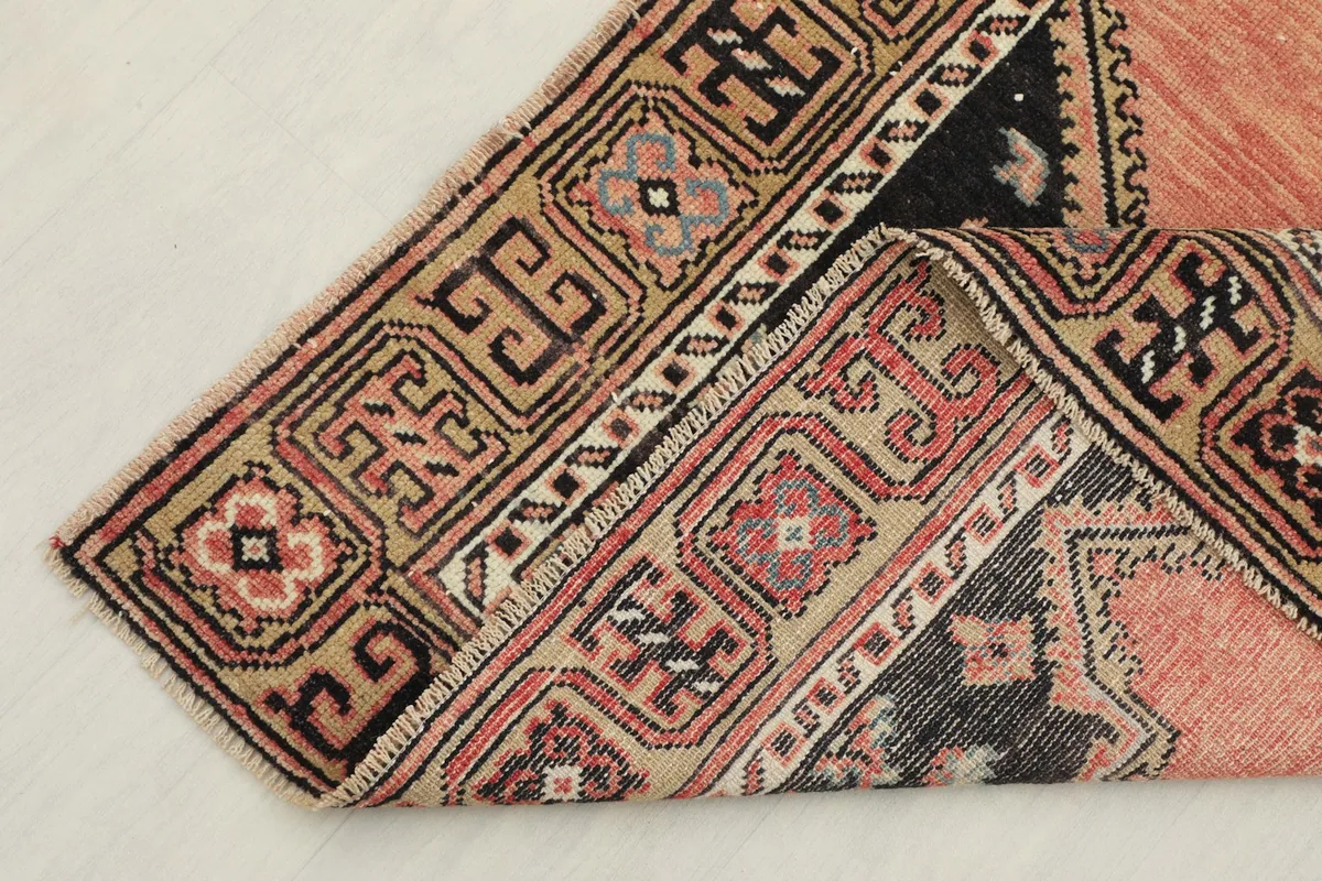 Corner of the runner folded to show the wool pile texture and the detailed border design