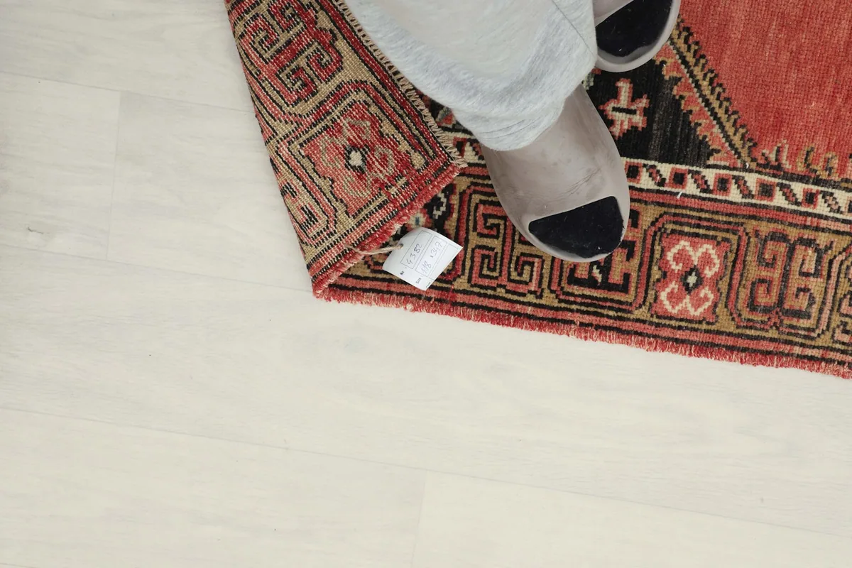 Feet on the runner's corner, highlighting the low pile and the texture of the vintage wool
