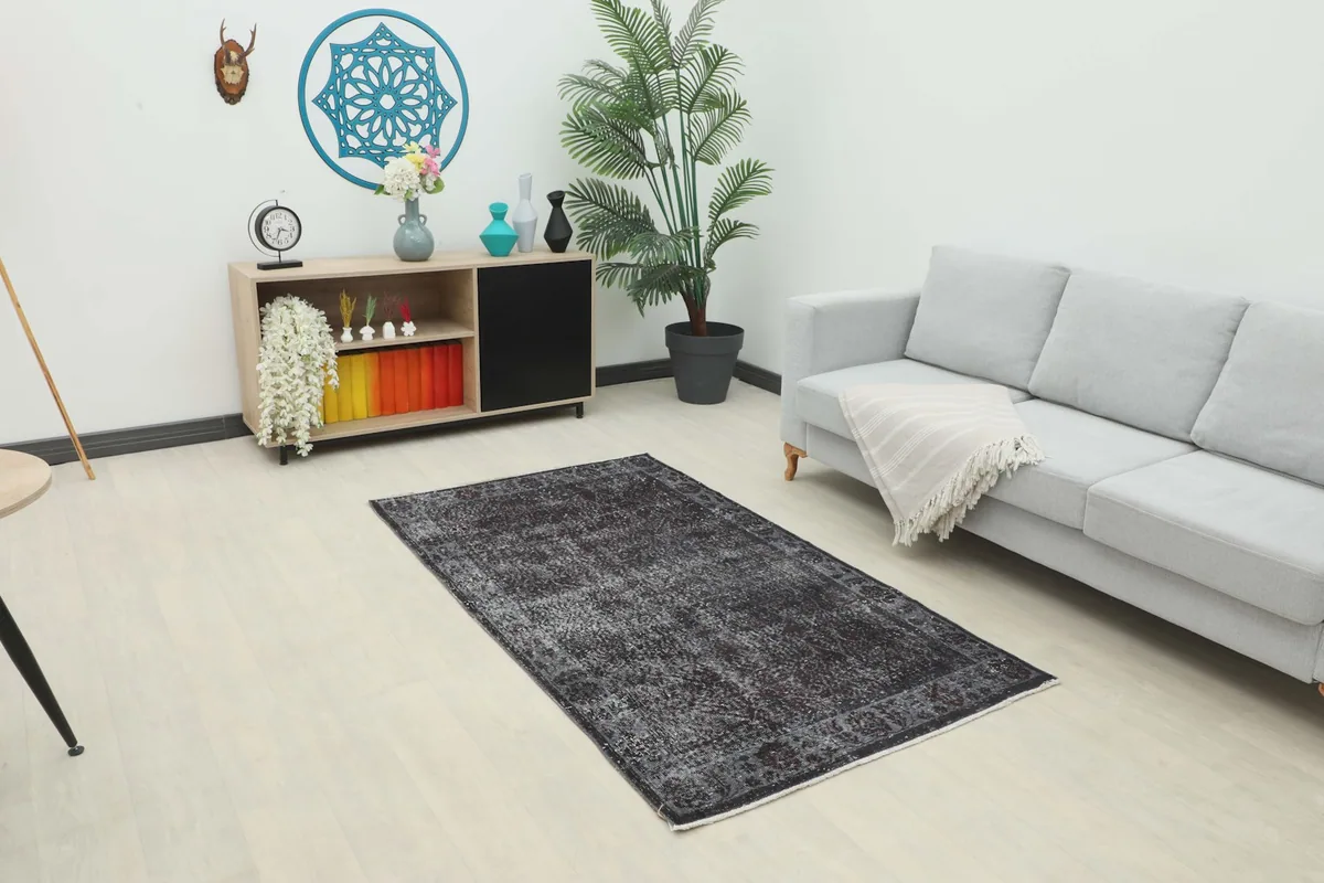 Charcoal gray vintage rug displayed in a modern living room setting with light furniture.