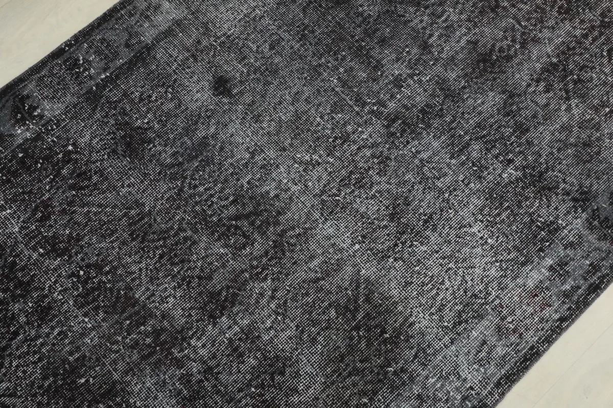 Detailed view of the rug's field, showcasing the distressed texture and faded charcoal and gray hues.
