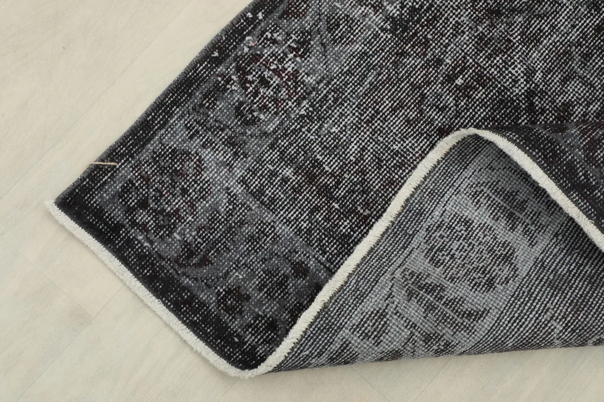 Close-up of the folded corner, highlighting the low pile and the contrast between the front and back of the rug.