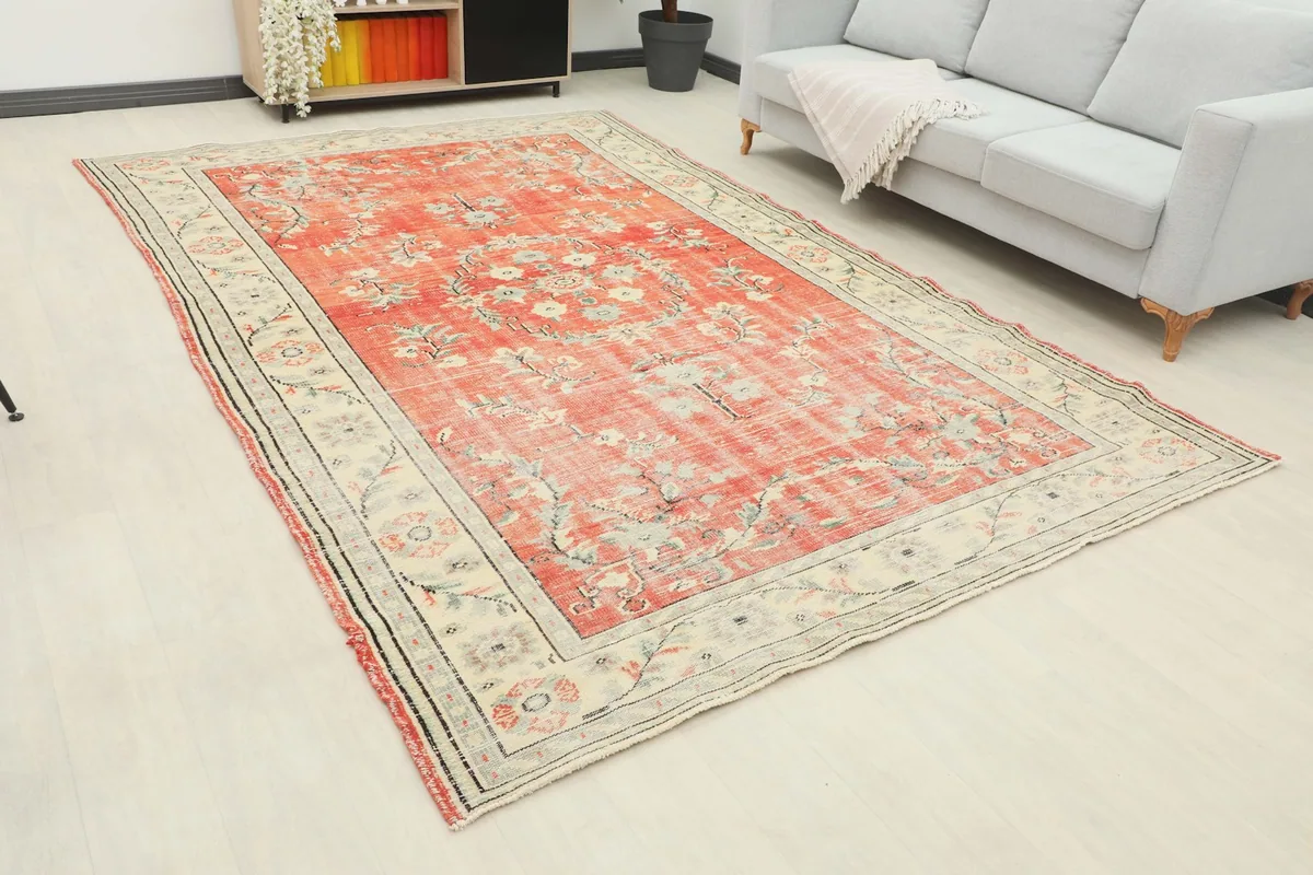 Angle view of the rust floral rug in a room, highlighting its size and placement next to furniture