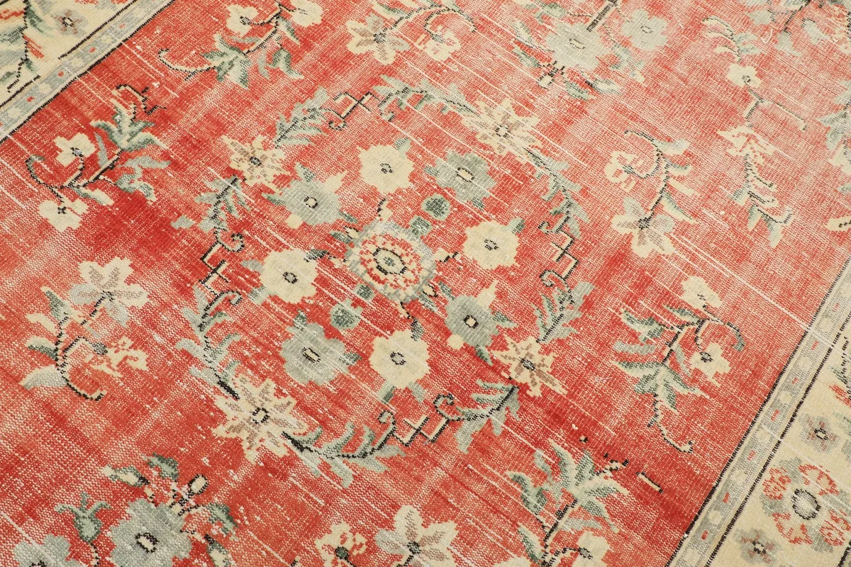 Detailed view of the central floral medallion and surrounding motifs in rust, blue, and ivory