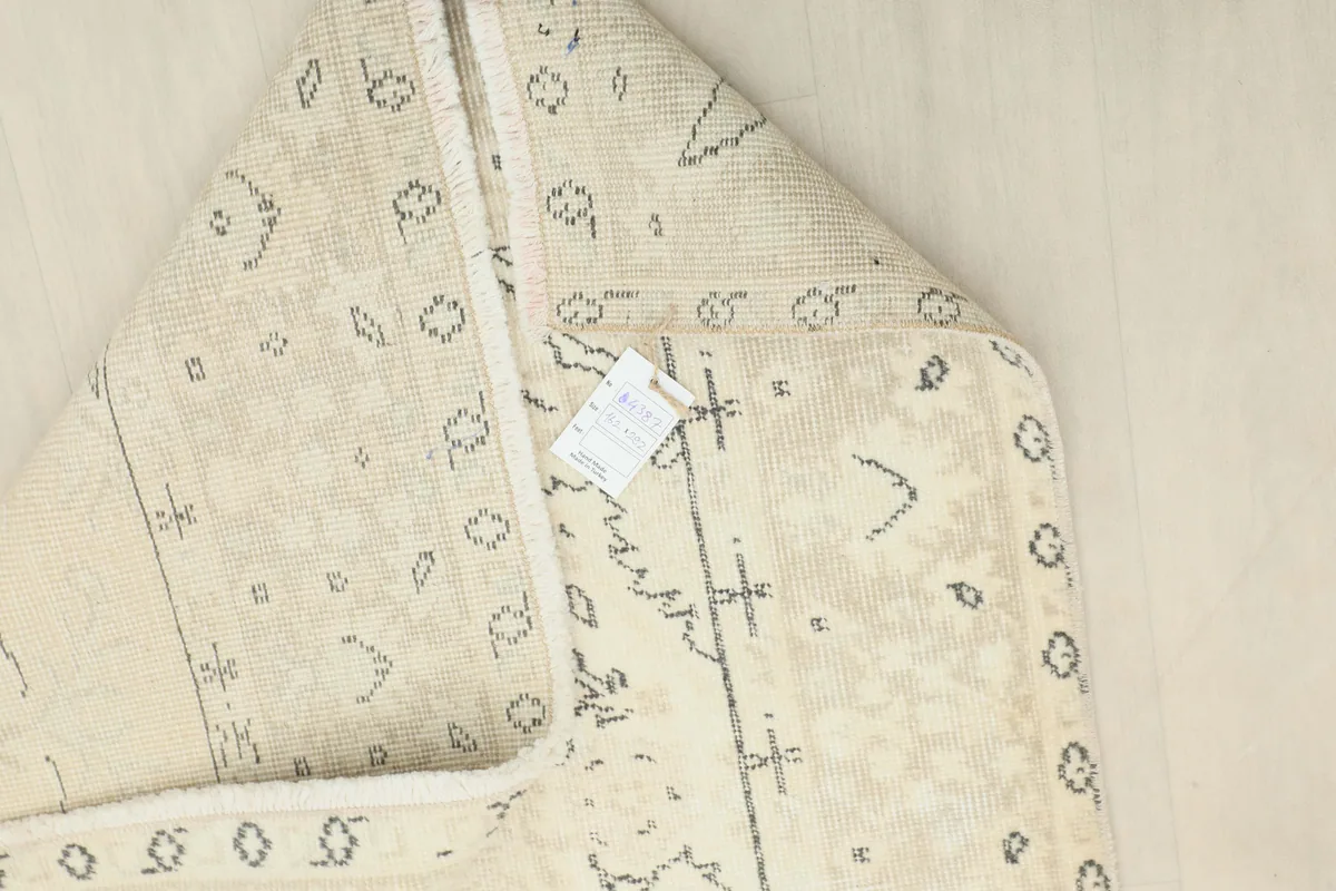 Close-up of the rug's back, displaying the hand-knotted construction and material tag.