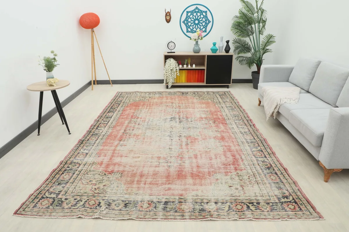 Full view of the 7'8" x 10'11" vintage rose and navy rug in a living room, viewed from a distance.