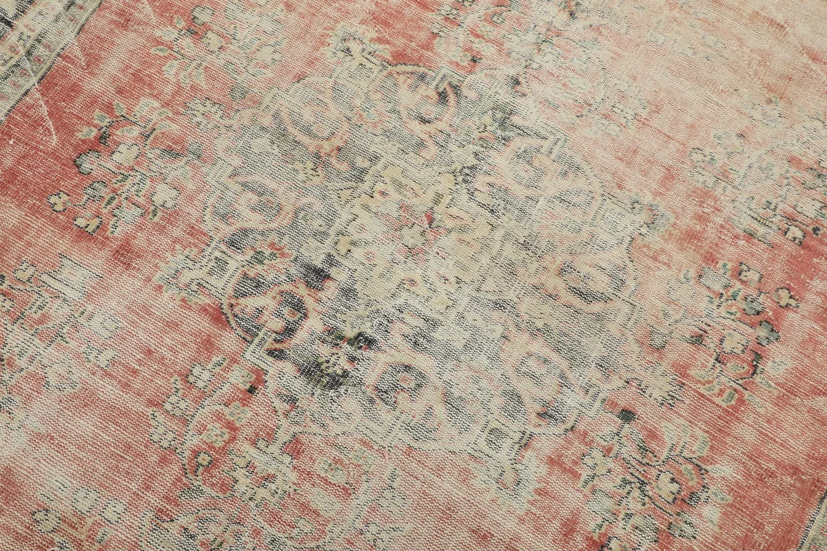 Detailed view of the central medallion, showing faded rose, navy, and beige tones with visible wear.