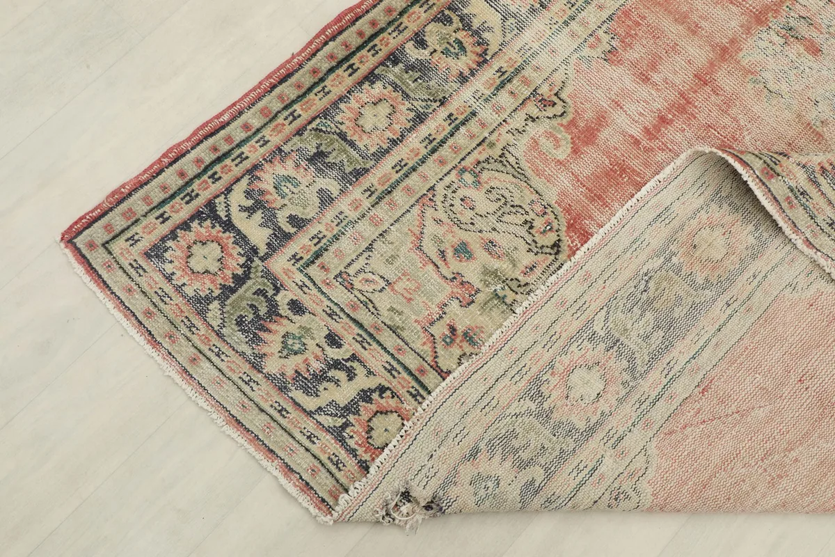 Corner of the rug folded back to reveal the cotton foundation and reverse side of the hand-knotting.