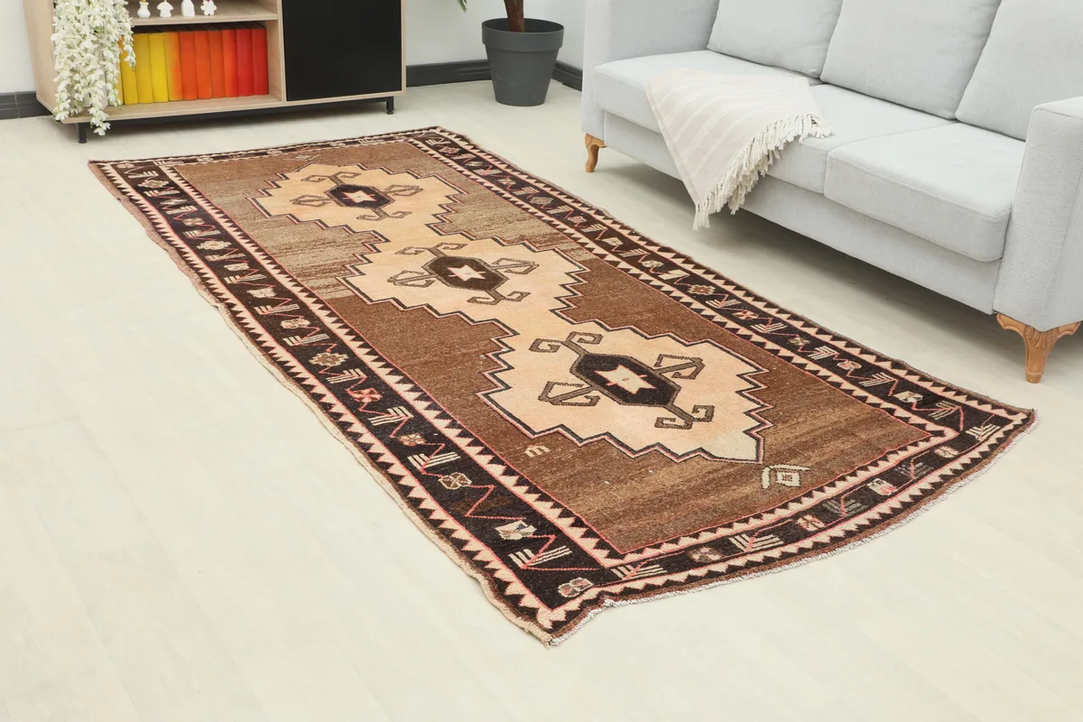 Beige Brown Tribal Anatolian Rug from an elevated angle in a room with a sofa.