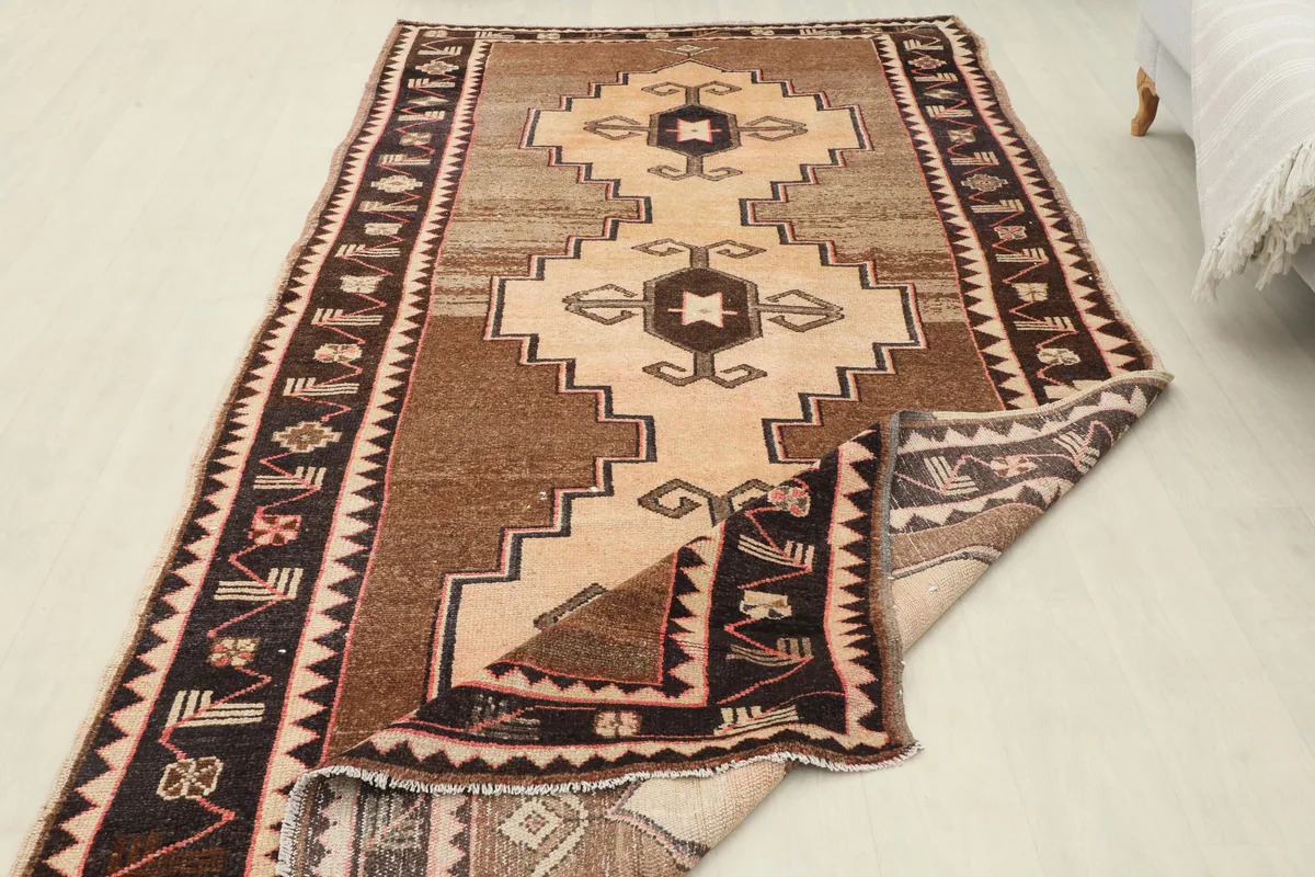 The Beige Brown Tribal Anatolian Rug partially folded to reveal the backside of the hand-knotted weave.