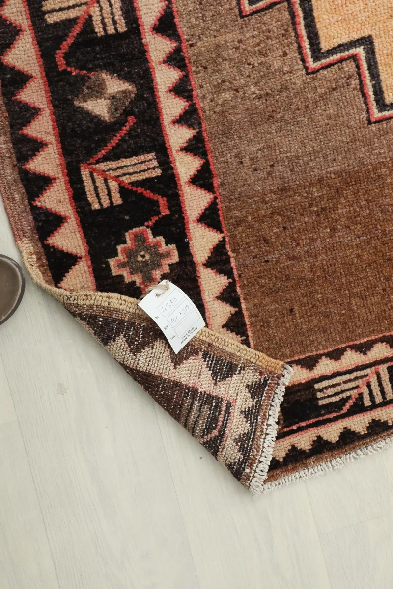 Corner of the Beige Brown Tribal Anatolian Rug with a product tag attached, showing texture.