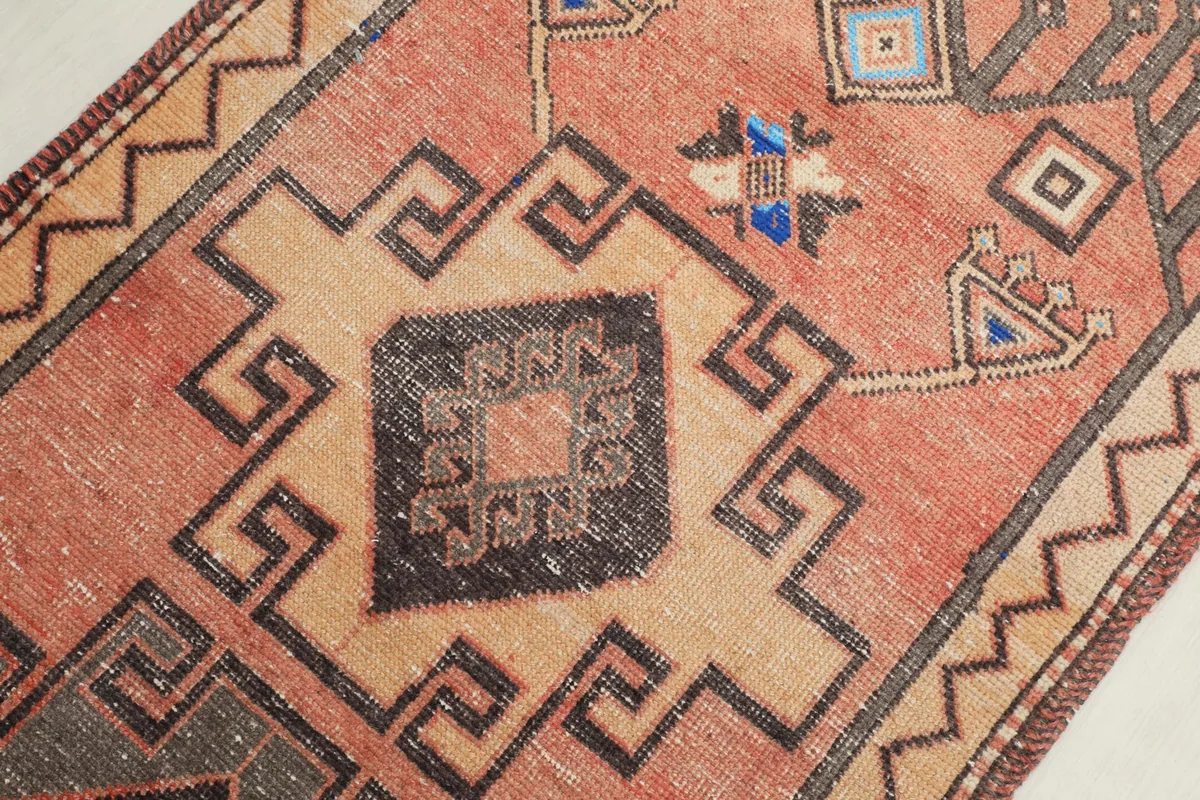Detailed shot of the central medallion and surrounding geometric elements in rust, tan, and charcoal