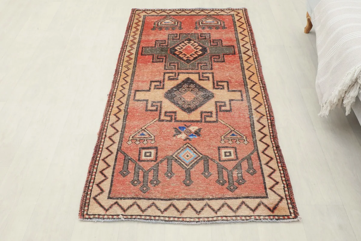 Overhead view of the small rust and charcoal vintage rug laid out on a light floor