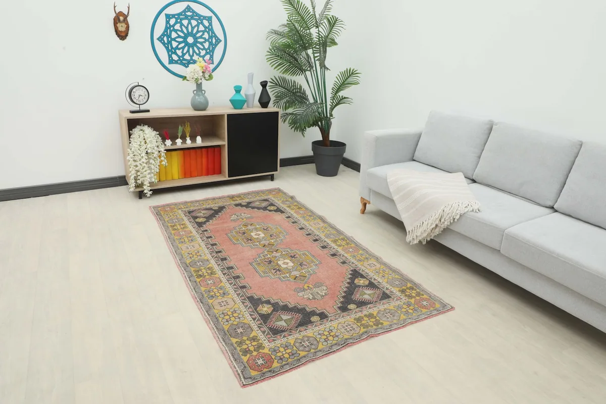 Vintage Anatolian rug displayed in a modern living room setting with a light gray sofa and wooden shelf.