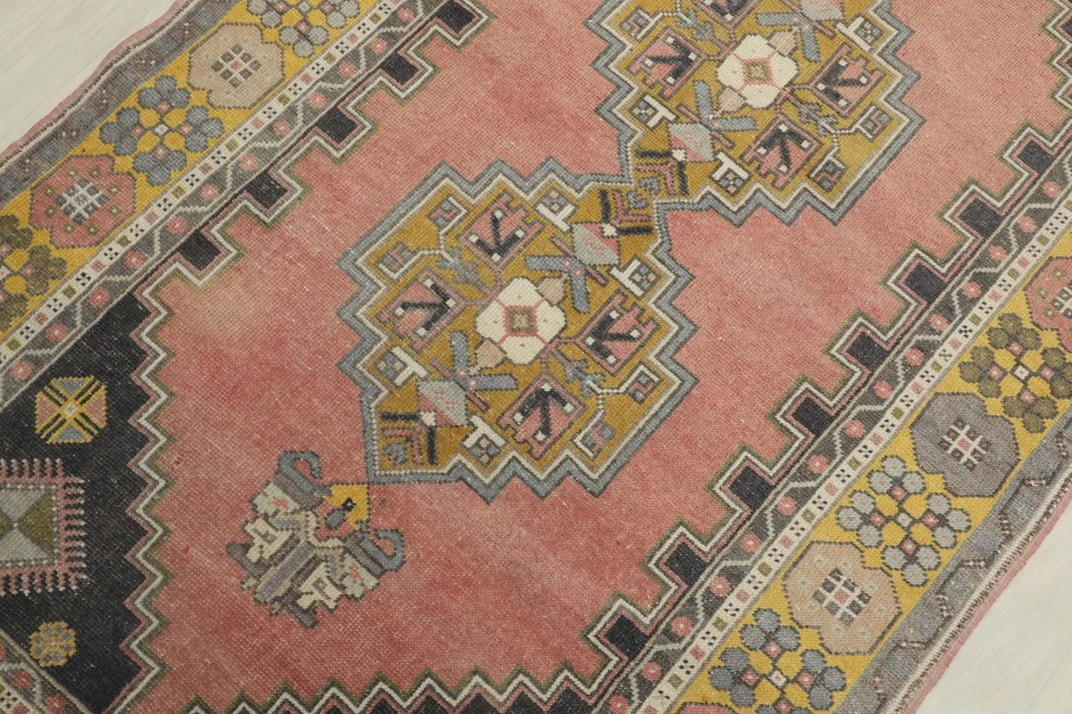 Detailed view of the central geometric medallion-like motif in gold, ivory, and olive tones.