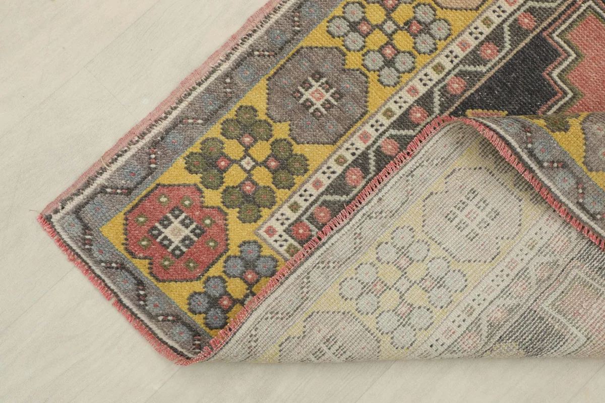 Corner of the rug folded back to show the cotton foundation and the reverse side of the hand-knotting.