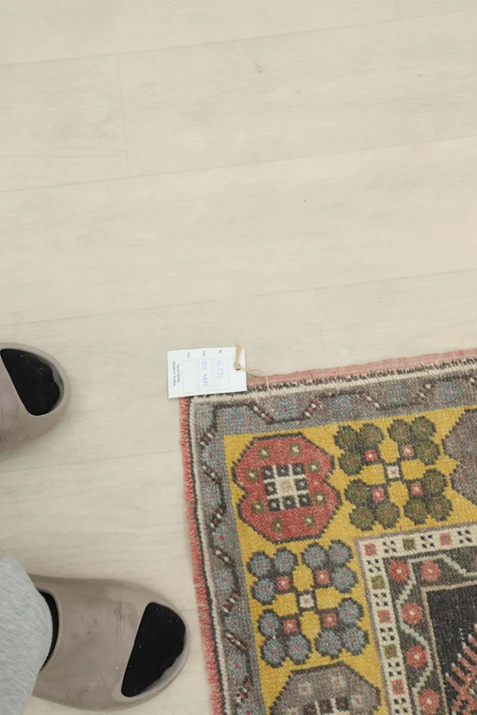 Overhead view showing the rug's corner with a size tag and feet for scale, emphasizing its small area rug size.