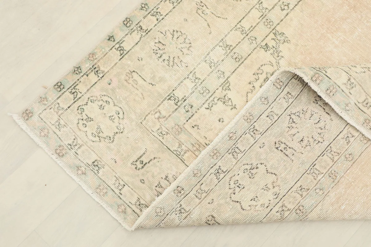 Corner of the rug folded back, providing a view of the reverse side and knotting detail.