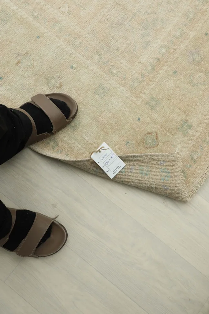 Close-up of the rug's low wool pile and a size tag near a foot for scale
