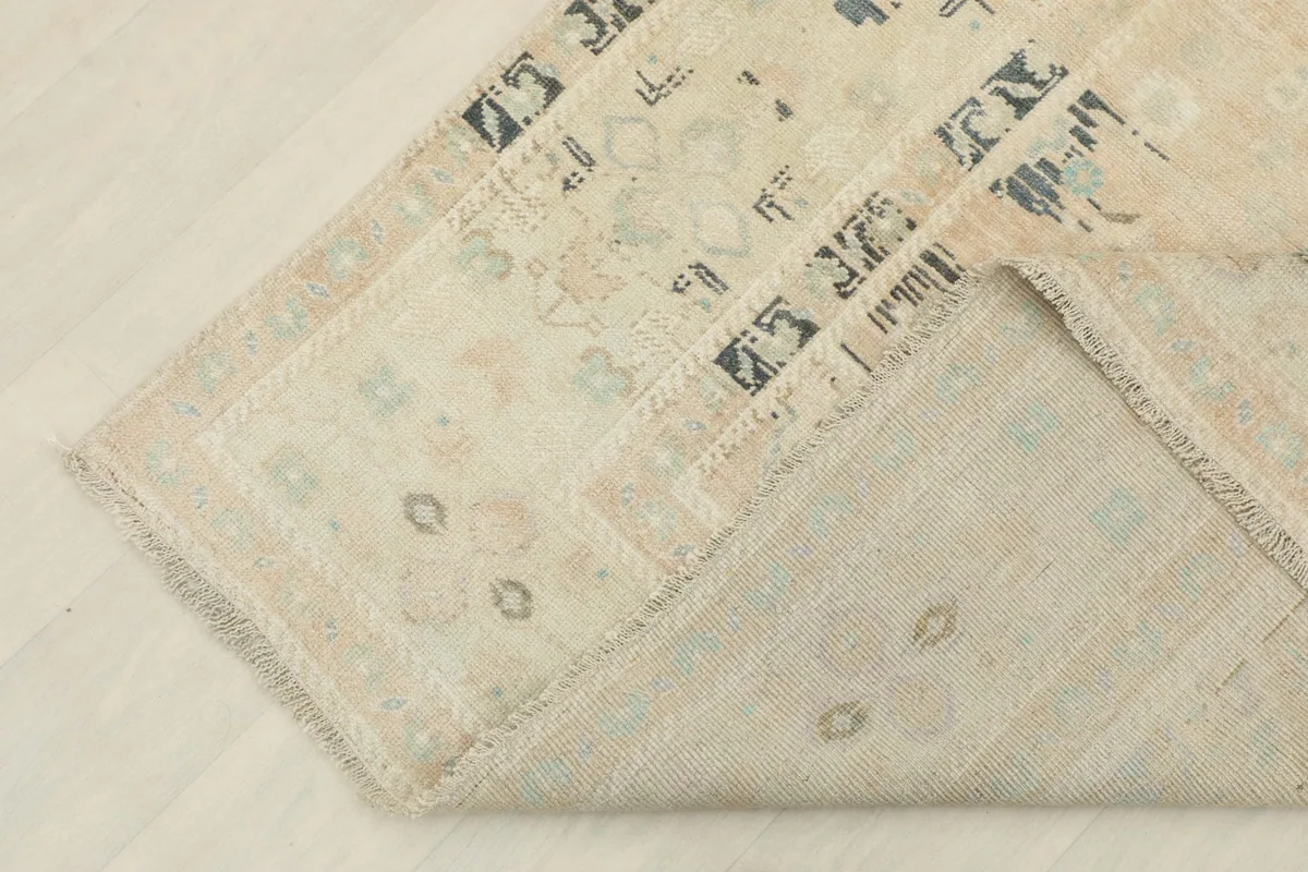 Corner of the rug folded back, showing the cotton foundation and hand-knotted construction