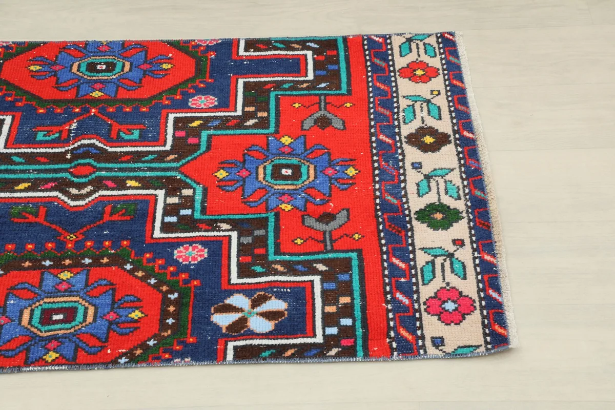 Close-up of the rug's upper right section, showing the red field and beige floral border