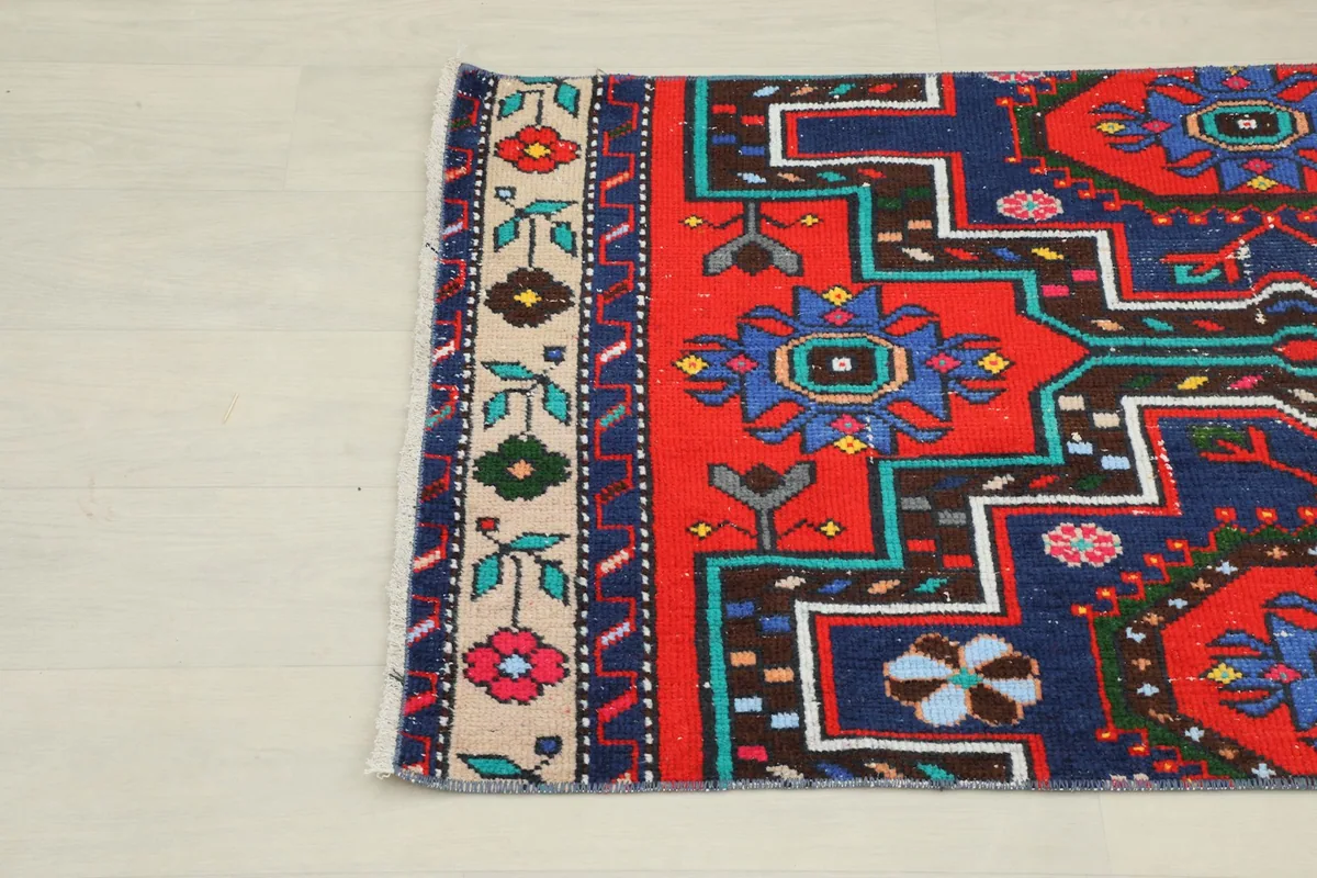 Close-up of the rug's upper left section, detailing the red field and beige floral border